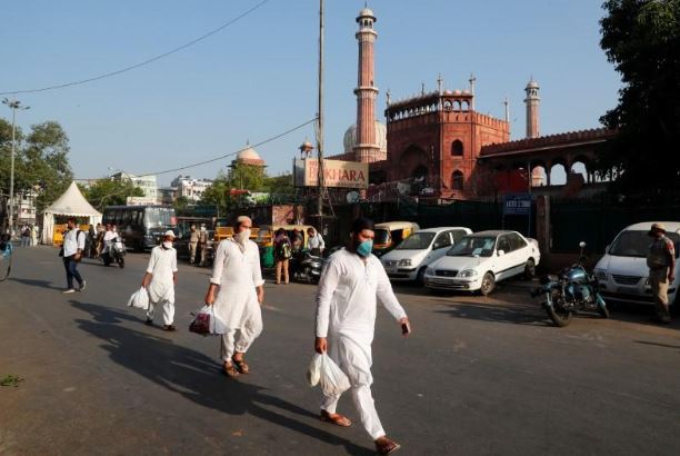 مسلمون يضعون كمامات يمرون بأحد المساجد في عيد الفطر بدلهي يوم 25 مايو 2020. تصوير: عدنان عبيدي - رويترز